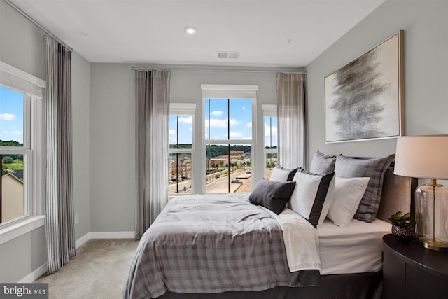 carpeted bedroom featuring visible vents, multiple windows, and baseboards