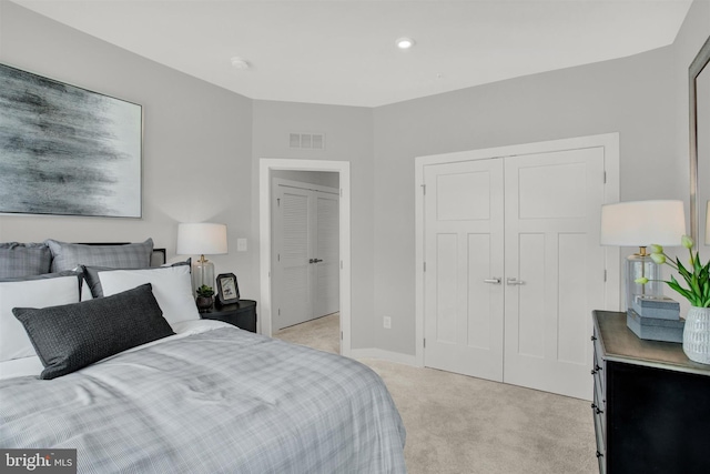 bedroom with light colored carpet, visible vents, a closet, and baseboards