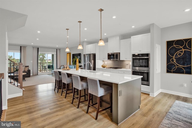 kitchen featuring a spacious island, backsplash, white cabinets, and stainless steel appliances