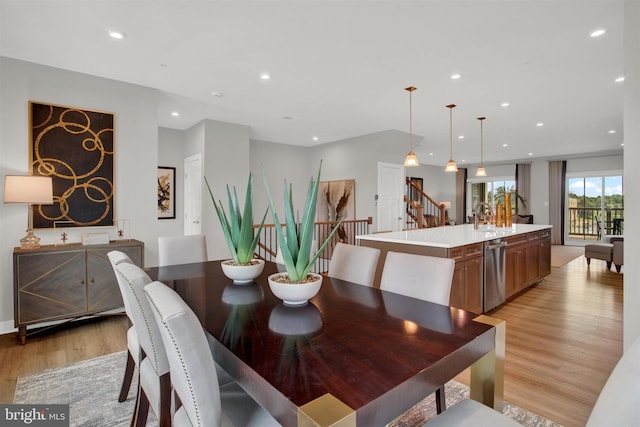 dining room with light wood finished floors, recessed lighting, and stairs