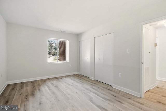 unfurnished bedroom with light wood-type flooring, visible vents, and baseboards