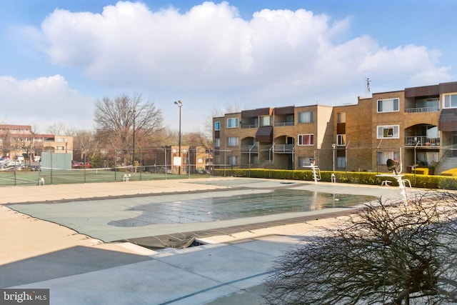 view of community with a tennis court and fence