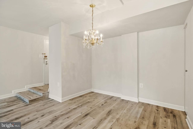 unfurnished dining area with an inviting chandelier, baseboards, and wood finished floors