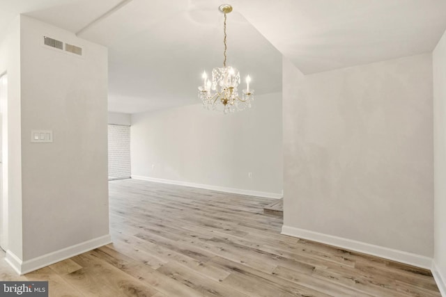 empty room featuring visible vents, an inviting chandelier, baseboards, and light wood-style floors