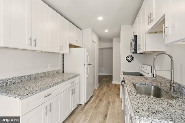 kitchen with white appliances, white cabinetry, and a sink