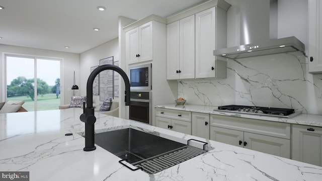 kitchen with stainless steel gas stovetop, wall oven, white cabinetry, wall chimney range hood, and tasteful backsplash