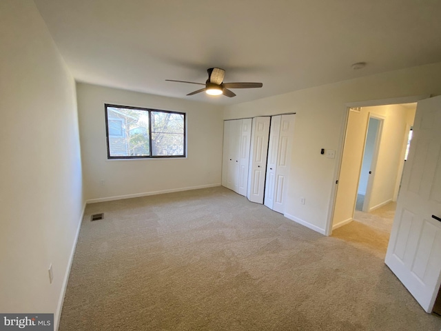 unfurnished bedroom featuring visible vents, a closet, baseboards, light colored carpet, and ceiling fan