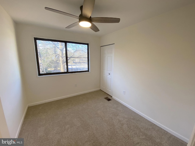 unfurnished room with visible vents, a ceiling fan, baseboards, and light carpet