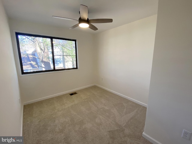 carpeted spare room featuring visible vents, baseboards, and ceiling fan