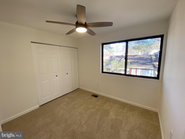 unfurnished bedroom with a closet, visible vents, light colored carpet, and baseboards