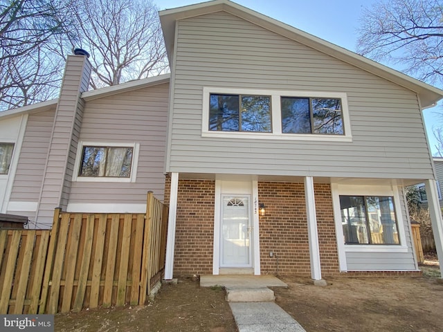 view of front of house with brick siding and fence