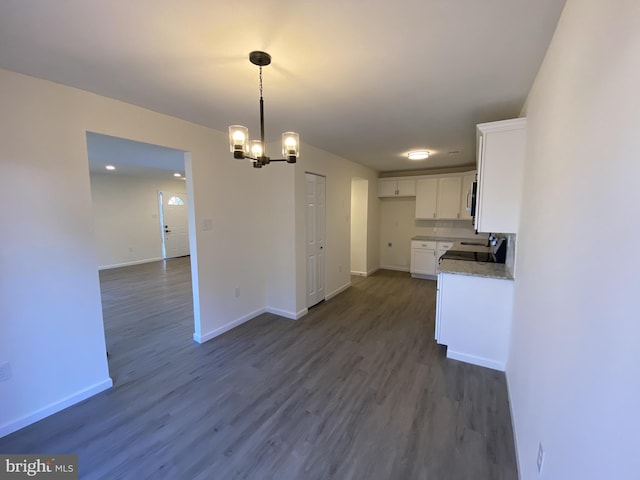 kitchen with white cabinetry, dark wood finished floors, baseboards, and a chandelier