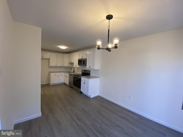 kitchen featuring baseboards, appliances with stainless steel finishes, dark wood-style floors, white cabinetry, and a sink