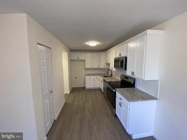 kitchen featuring a sink, stainless steel appliances, light stone countertops, and white cabinets