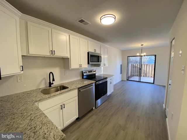 kitchen with a sink, a notable chandelier, appliances with stainless steel finishes, and white cabinetry