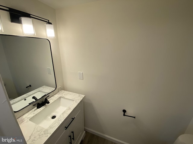 bathroom with vanity, wood finished floors, and baseboards