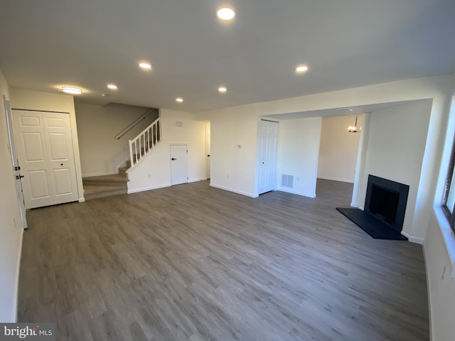 unfurnished living room featuring recessed lighting, baseboards, dark wood-style flooring, and stairs