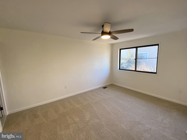 empty room featuring visible vents, light colored carpet, baseboards, and a ceiling fan