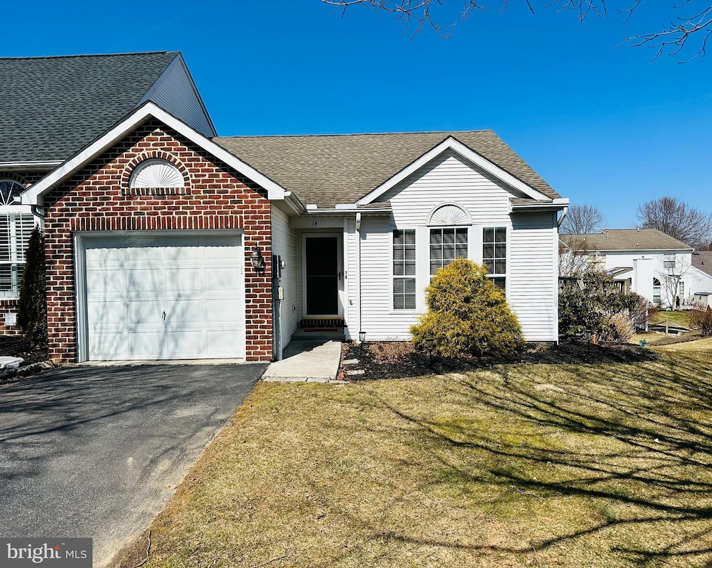 ranch-style home featuring a front lawn, driveway, roof with shingles, an attached garage, and brick siding