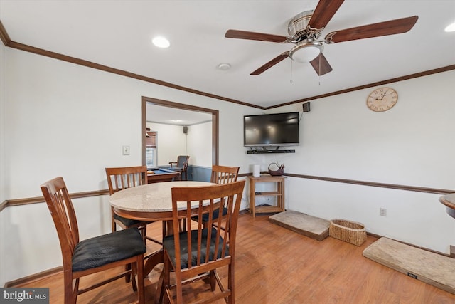 dining area featuring baseboards, a ceiling fan, wood finished floors, and crown molding