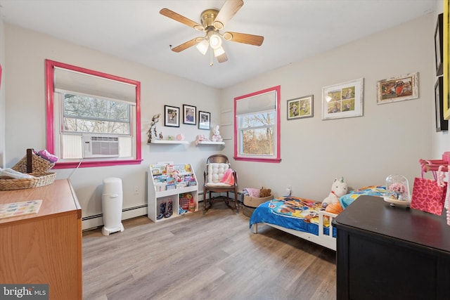 bedroom featuring multiple windows, a baseboard heating unit, and wood finished floors