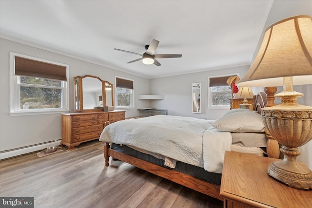 bedroom featuring crown molding, light wood-style flooring, a baseboard radiator, and ceiling fan