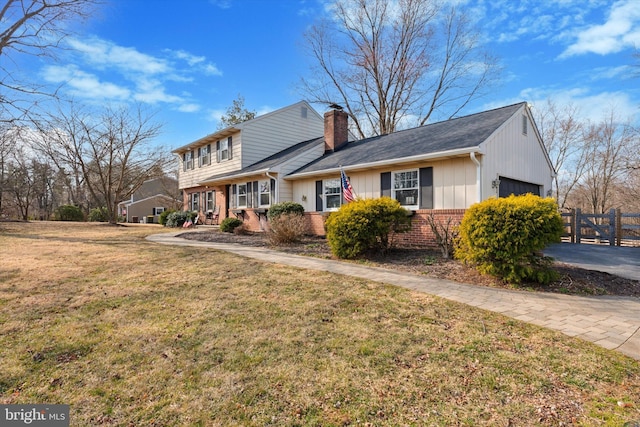 view of front of house with brick siding, a front lawn, fence, a chimney, and a garage