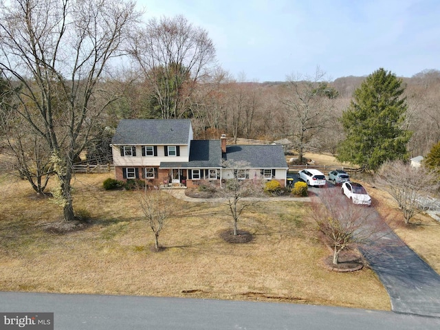 view of front of house with brick siding, a front yard, a chimney, and driveway