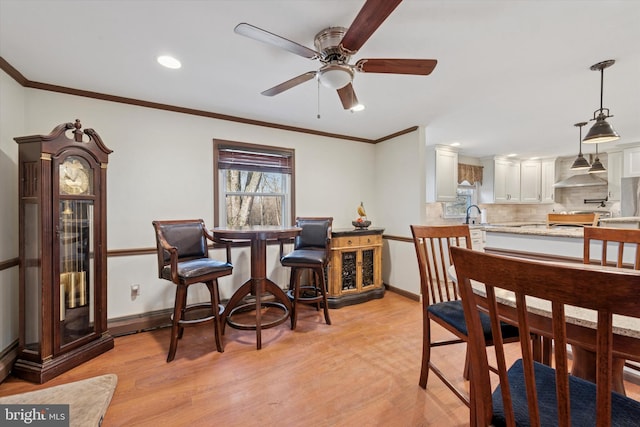 dining room featuring baseboards, a ceiling fan, light wood-style floors, and ornamental molding