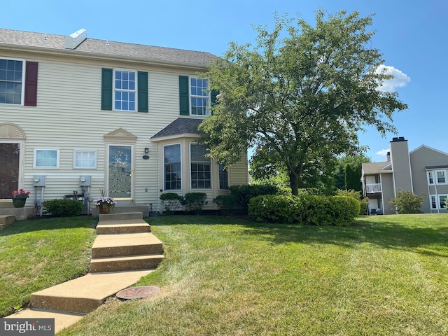 townhome / multi-family property featuring a front lawn and a shingled roof