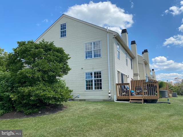 rear view of property featuring a yard, central AC, a deck, and a chimney