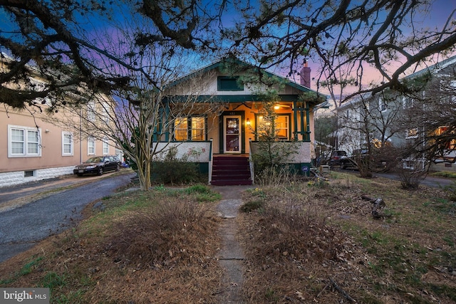 bungalow-style house featuring covered porch and a chimney