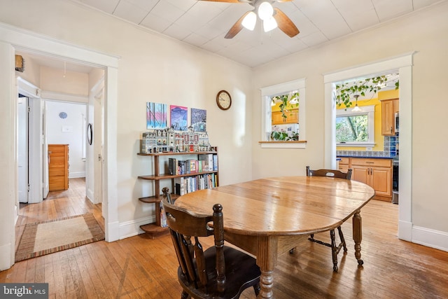 dining area featuring crown molding, a ceiling fan, baseboards, and light wood-style flooring