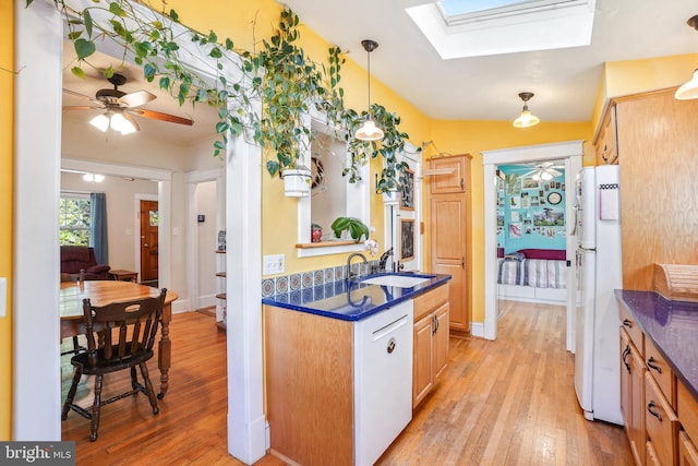 kitchen featuring a sink, dark countertops, a ceiling fan, and light wood finished floors