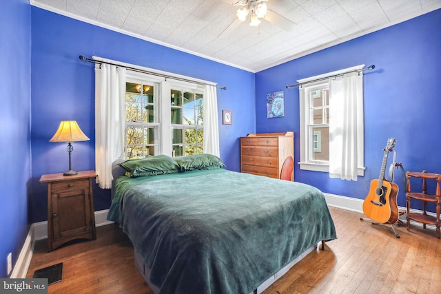bedroom with visible vents, baseboards, crown molding, and hardwood / wood-style floors