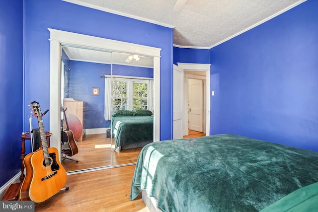 bedroom featuring crown molding, a ceiling fan, wood finished floors, and a closet