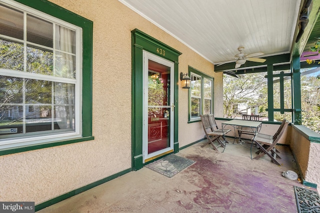 property entrance with ceiling fan, stucco siding, and covered porch