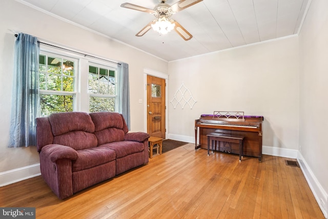 living area featuring crown molding, visible vents, baseboards, a ceiling fan, and light wood finished floors