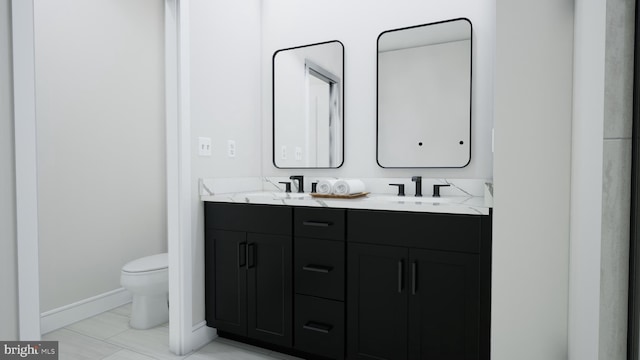 bathroom featuring a sink, baseboards, toilet, and double vanity