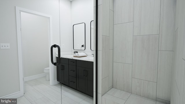 bathroom featuring toilet, baseboards, and double vanity