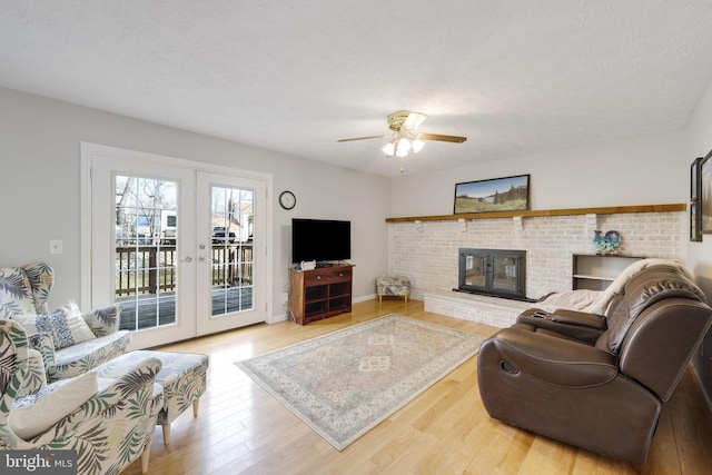 living room featuring french doors, a textured ceiling, wood finished floors, and a fireplace