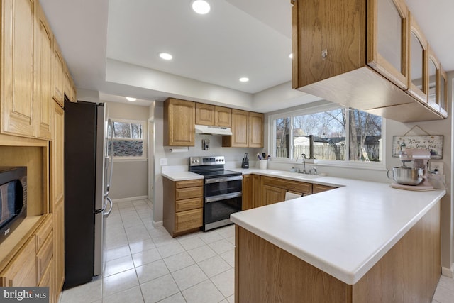 kitchen with under cabinet range hood, a wealth of natural light, appliances with stainless steel finishes, a peninsula, and a sink