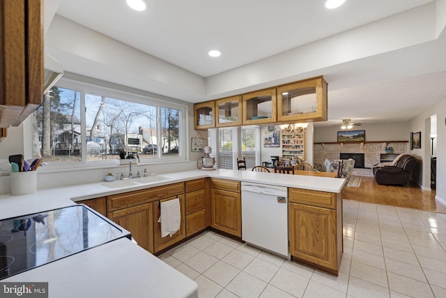 kitchen with light tile patterned floors, dishwasher, a peninsula, and a sink