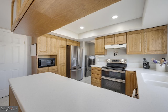 kitchen featuring washer and dryer, stainless steel appliances, under cabinet range hood, and light countertops