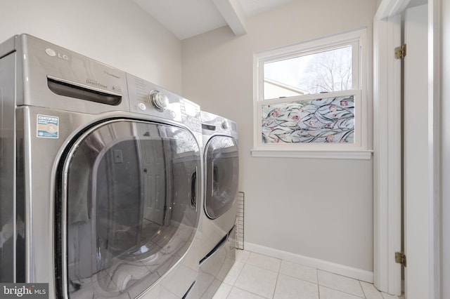 washroom featuring laundry area, light tile patterned floors, washing machine and dryer, and baseboards