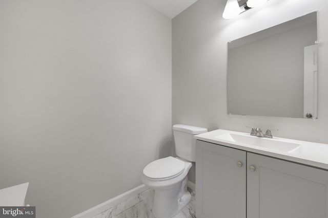 half bathroom with baseboards, toilet, marble finish floor, and vanity