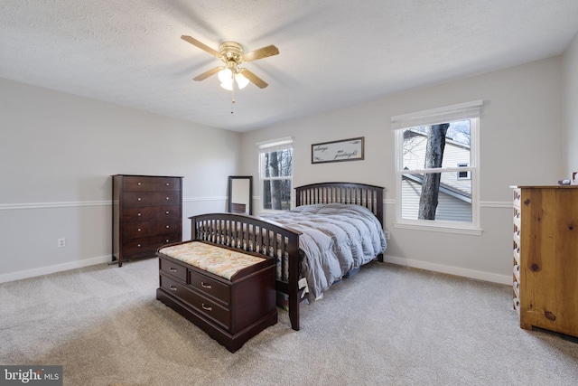 bedroom with baseboards, light carpet, a textured ceiling, and a ceiling fan