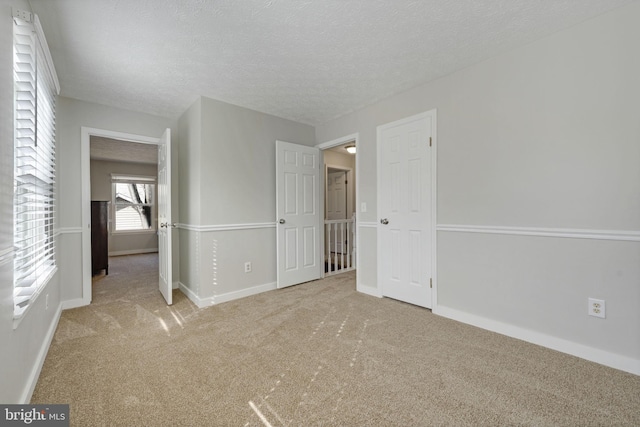 unfurnished bedroom featuring carpet flooring, baseboards, and a textured ceiling