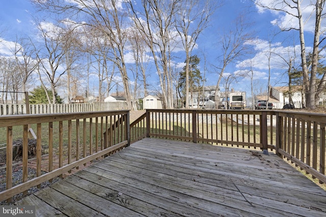 wooden deck with an outdoor structure, a fenced backyard, a residential view, and a shed