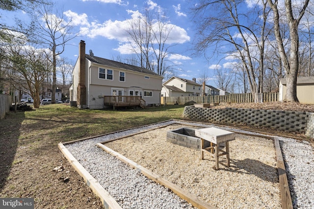 rear view of property featuring an outdoor fire pit, a wooden deck, a yard, a chimney, and fence private yard